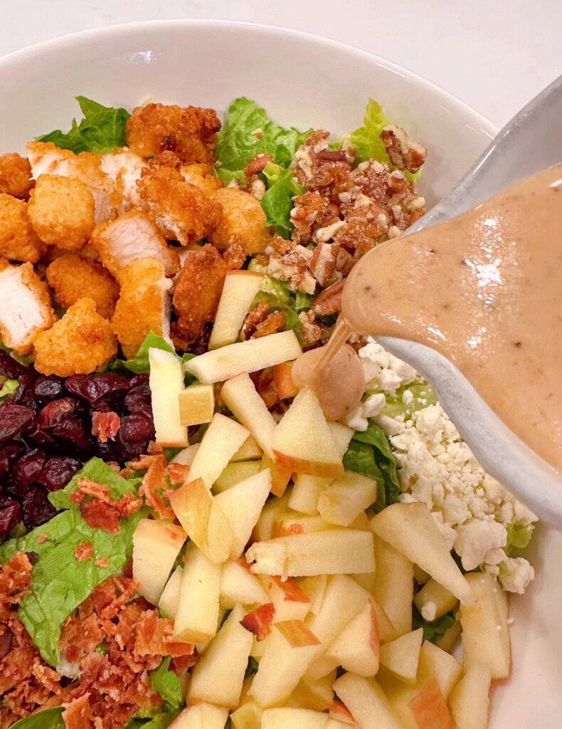 Pouring the dressing over the salad ingredients.