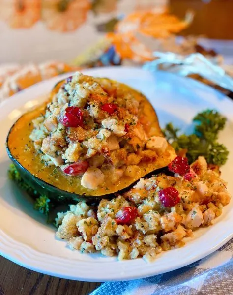Bowl filled with a beautiful stuffed acorn squash and an extra side of stuffing.
