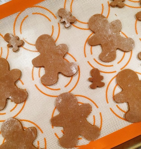 Spiced Gingerbread men cut out on baking sheets lined with silicone mats
