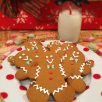 Gingerbread men cookies on a polka dot plate with a cup of milk for Santa.