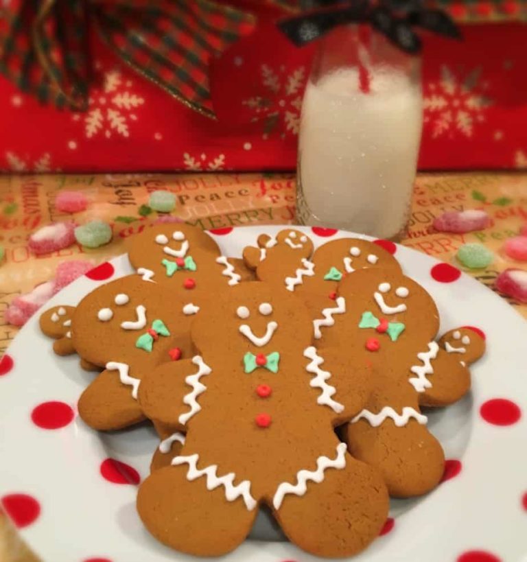 Gingerbread men cookies on a polka dot plate with a cup of milk for Santa.