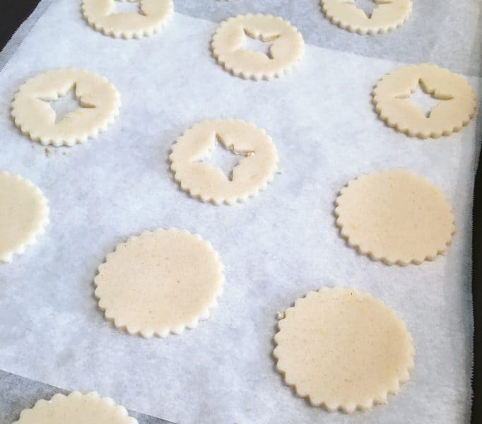 Cut out linzer cookies on baking sheet with parchment paper