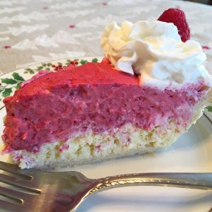 A slice of pie with a cheesecake bottom and raspberry filling on top.