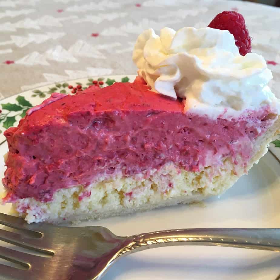 A slice of pie with a cheesecake bottom and raspberry filling on top