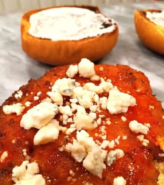 blue cheese sprinkled on top of buffalo chicken patty