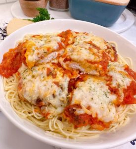 Huge bowl of Chicken Parmesan on top of a bed of Angel Hair Spaghetti.