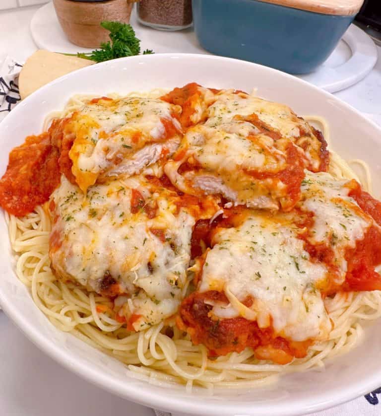 Huge bowl of Chicken Parmesan on top of a bed of Angel Hair Spaghetti.