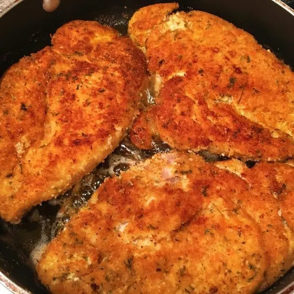 Breaded chicken breast frying in the skillet