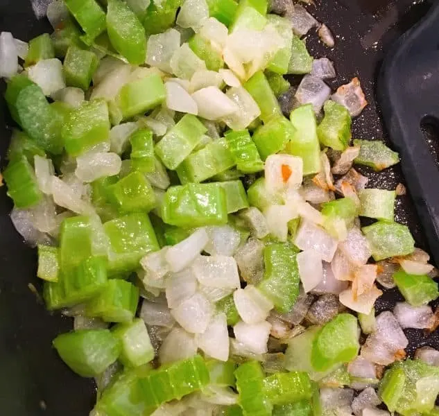 Skilled full of chopped celery and onions being sauteed