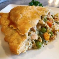 A large slice of chicken pot pie with chicken, vegetables and a flaky golden crust