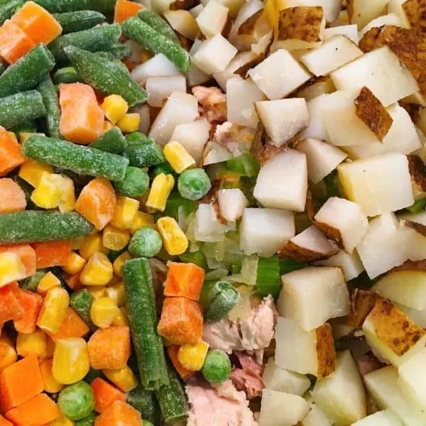 Adding frozen vegetables to potatoes and chicken