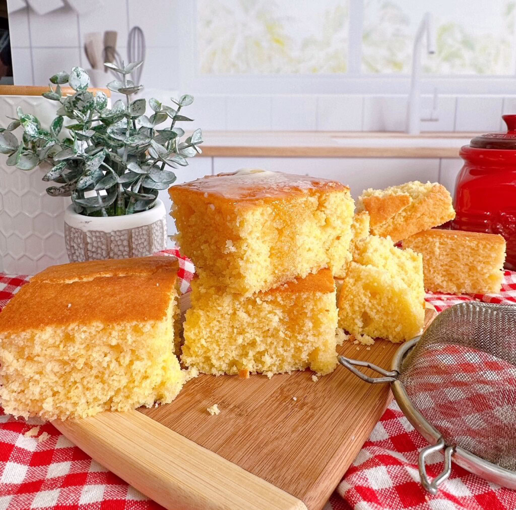 Stacked butter cornbread on a wooden cutting block.