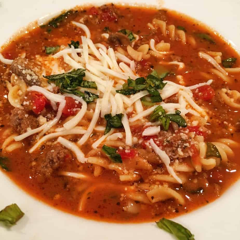 A bowl of beefy noodle soup with Italian herbs and spices with cheese and parsley on top