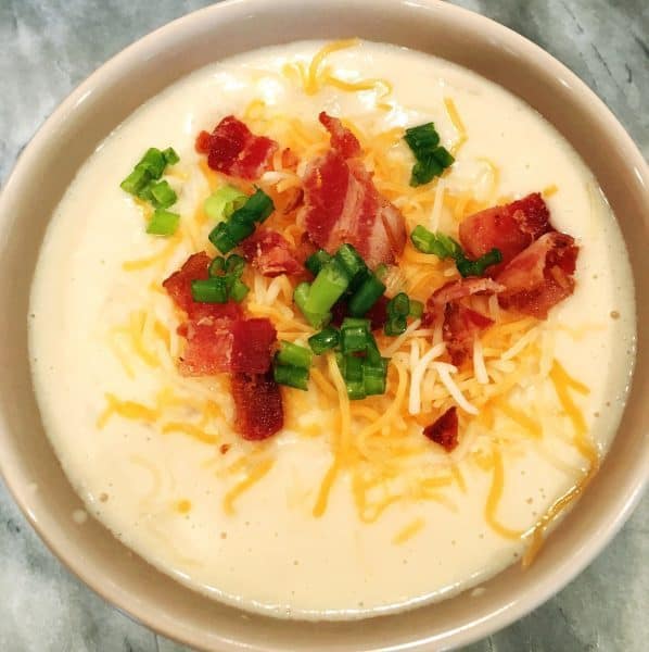 Slow Cooker Potato Soup topped with created cheese, bacon, and chives