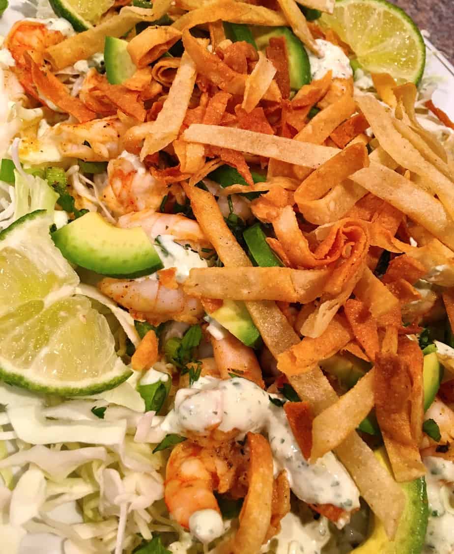 A taco salad made with shrimp, avocado, cabbage, lime and seasonings