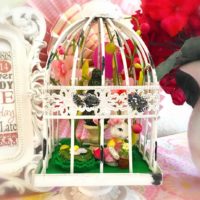 A white bird cage with various Easter decorations inside