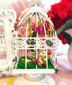 A white bird cage with various Easter decorations inside