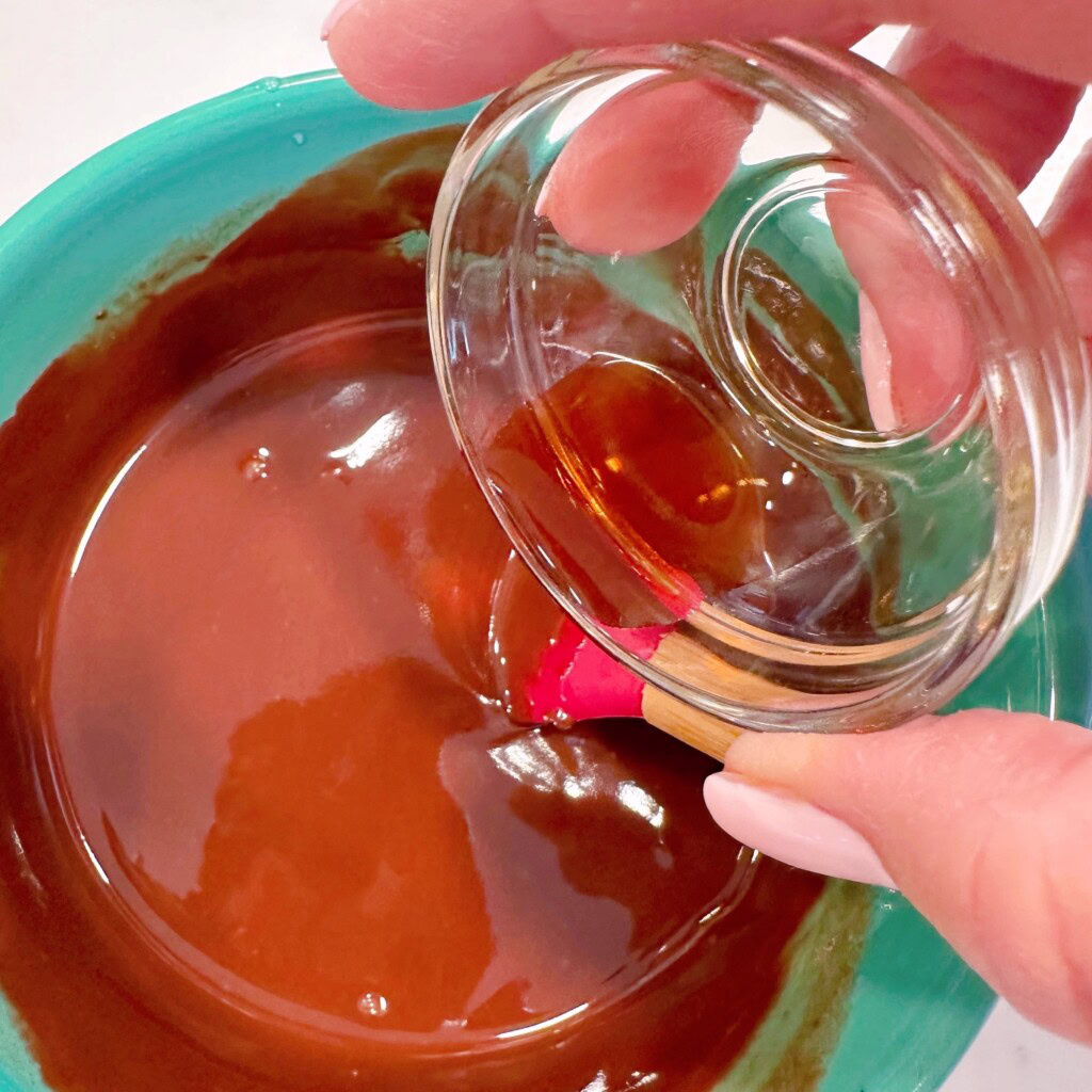 Melted chocolate chips in small ceramic bowl adding vanilla extract.
