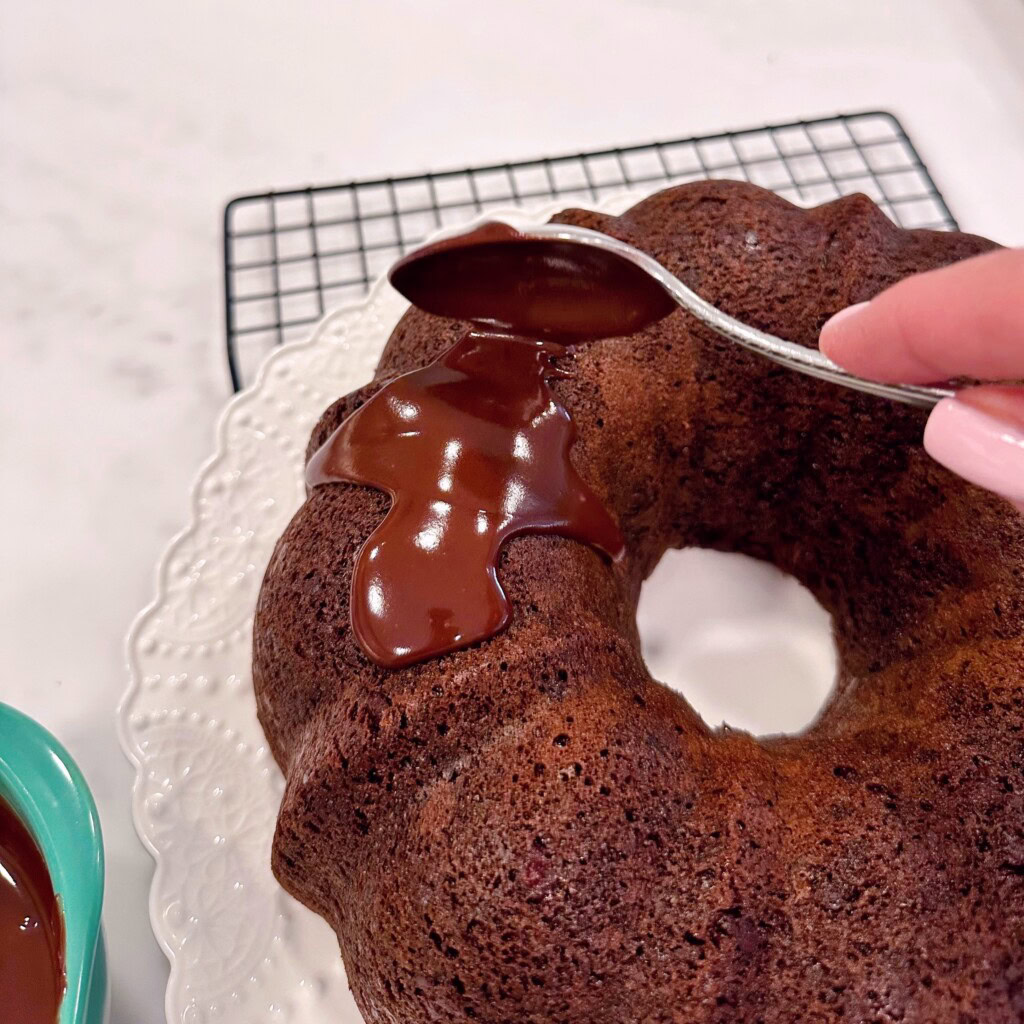 Pouring Satin Glaze over the top of the chocolate bundt cake.