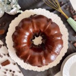 Overhead photo of Too Much Chocolate bundt cake on a white cake plate with a chocolate satin drizzle.