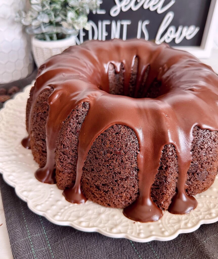 Side view of too much chocolate cake on a white cake plate.