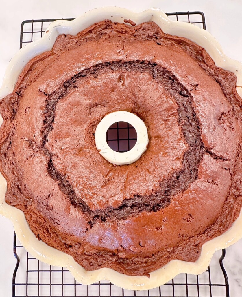 Baked Too Much Chocolate cake in the bundt pan on a cooling rack.