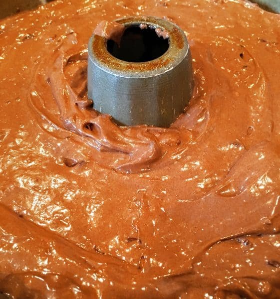 Too much chocolate cake in a prepared bundt cake pan ready for the oven.