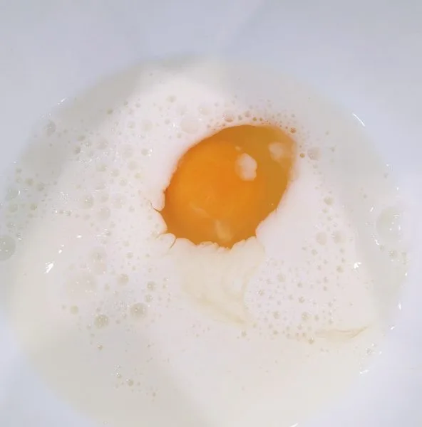 Milk and egg in a bowl for blueberry muffins