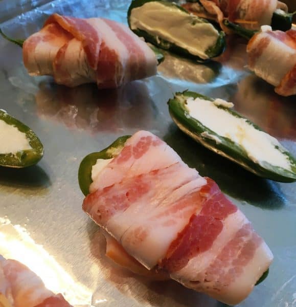 Fresh Jalapeno Poppers sliced in half, stuffed with cream cheese, and wrapped in bacon.
