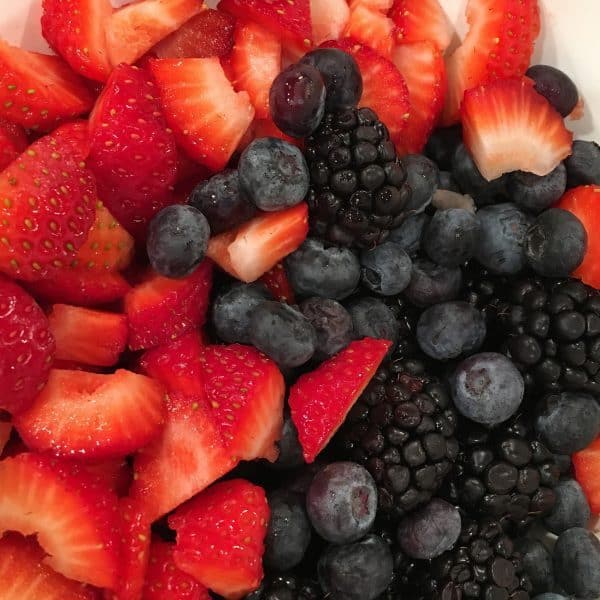 Fresh cut up strawberries, blueberries, and blackberries in a bowl