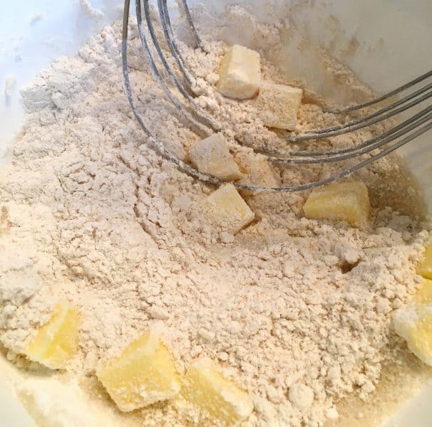Flour ingredients and butter cubes being cut into flour