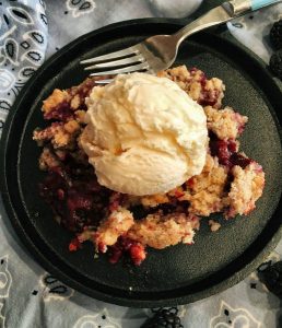 A berry cobbler with a scoop of ice cream on top