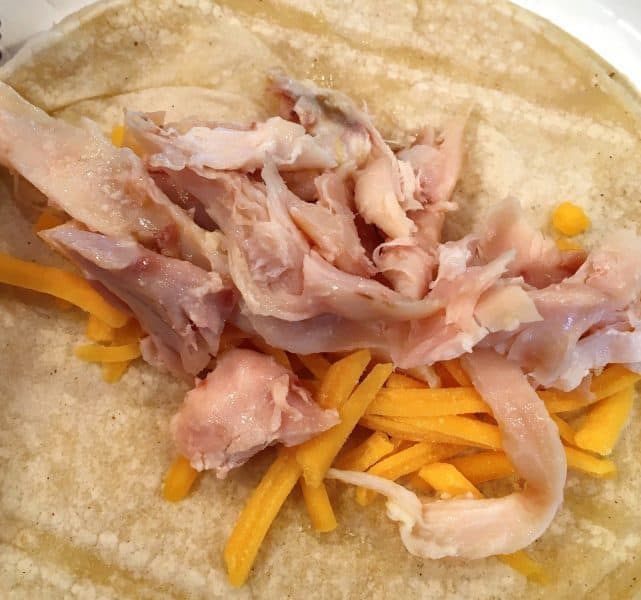 Corn tortilla filled with shredded chicken, and grated cheese.
