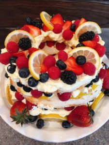 Layered Easy Lemon Berry Angle Food Cake with fresh berries piled high.
