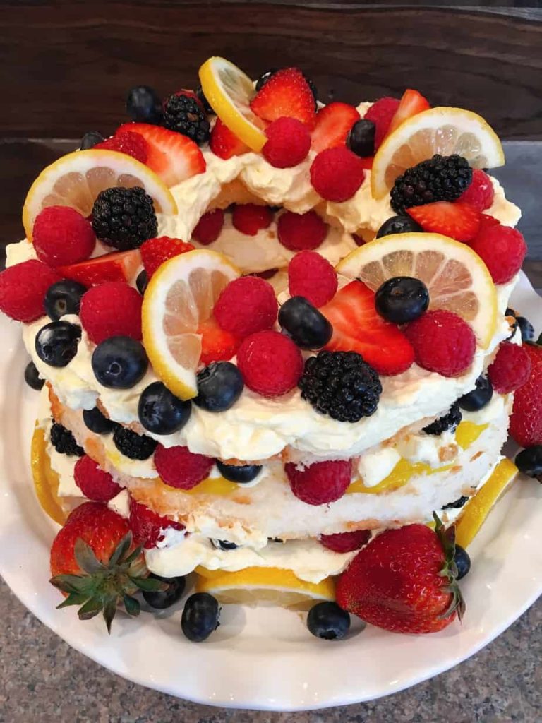 Layered Easy Lemon Berry Angle Food Cake with fresh berries piled high.