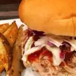 Pulled pork sandwich with potato wedges.