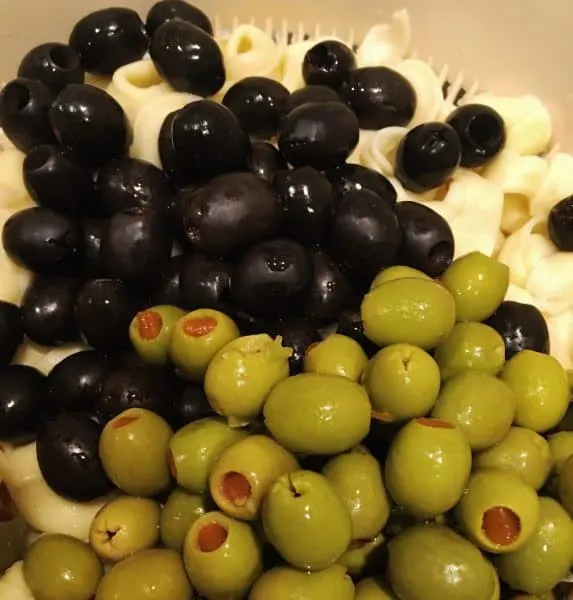 Olives, both green and black, with tortellini in strainer