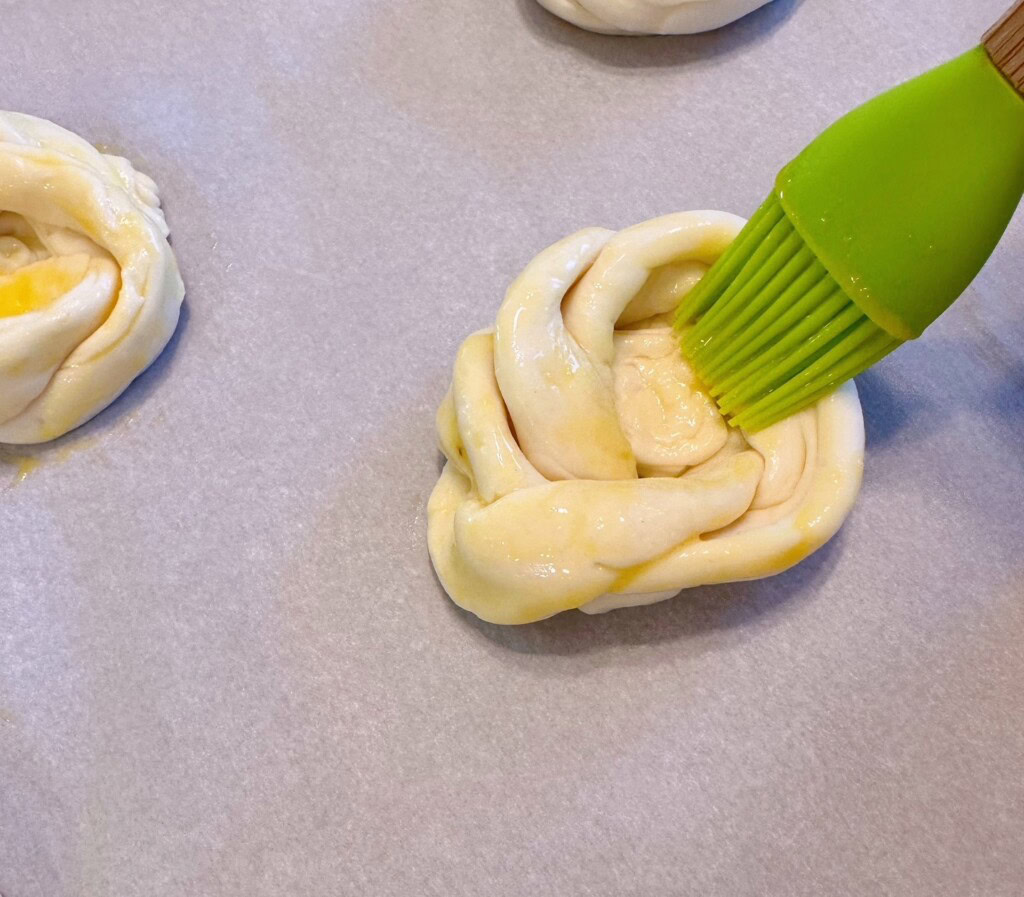 Brushing knots with egg wash.