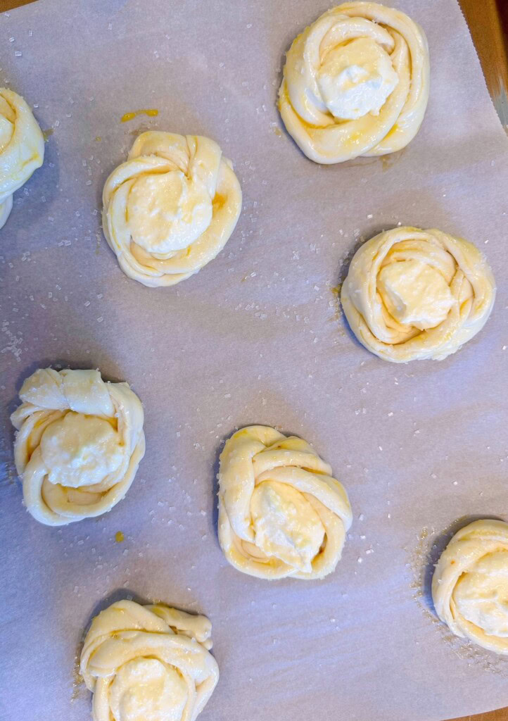 Filling pastry knots with cream cheese filling.