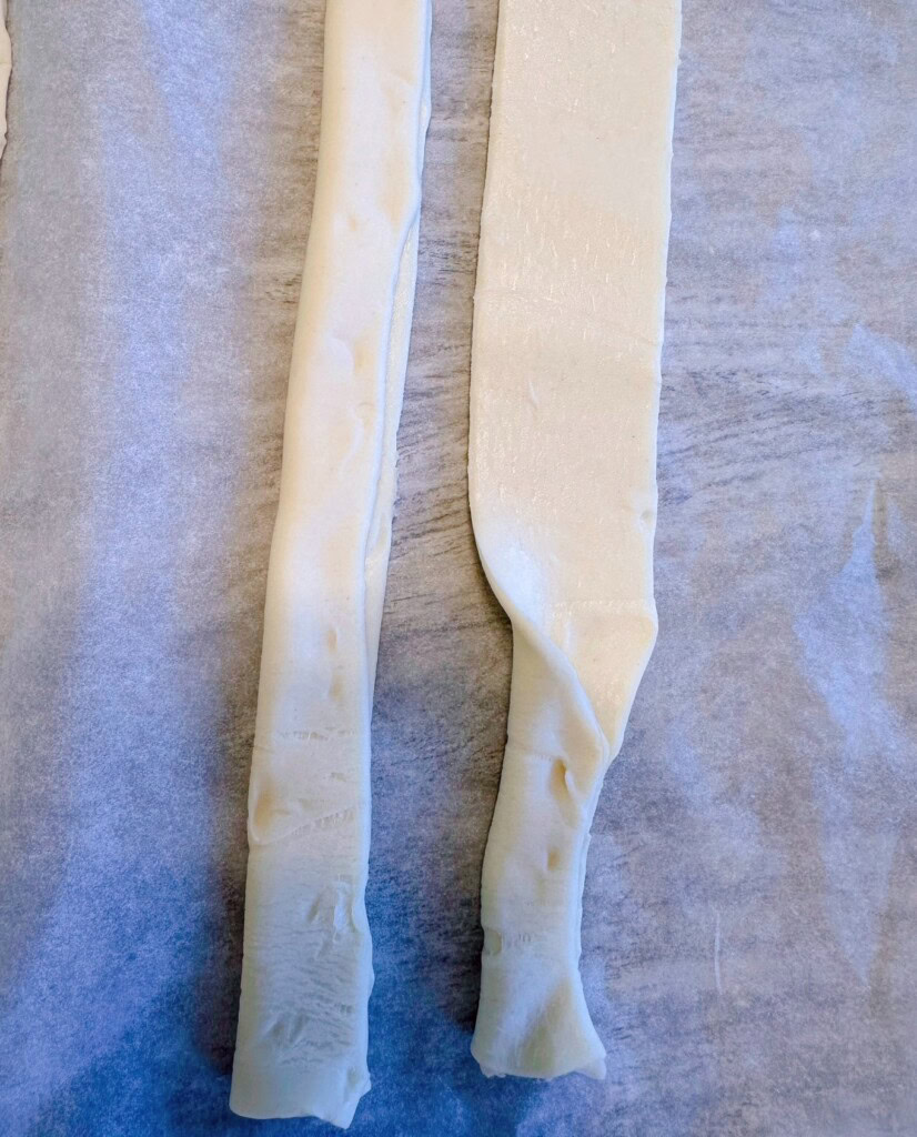 Pinching the strips of puff pastry on parchment paper.