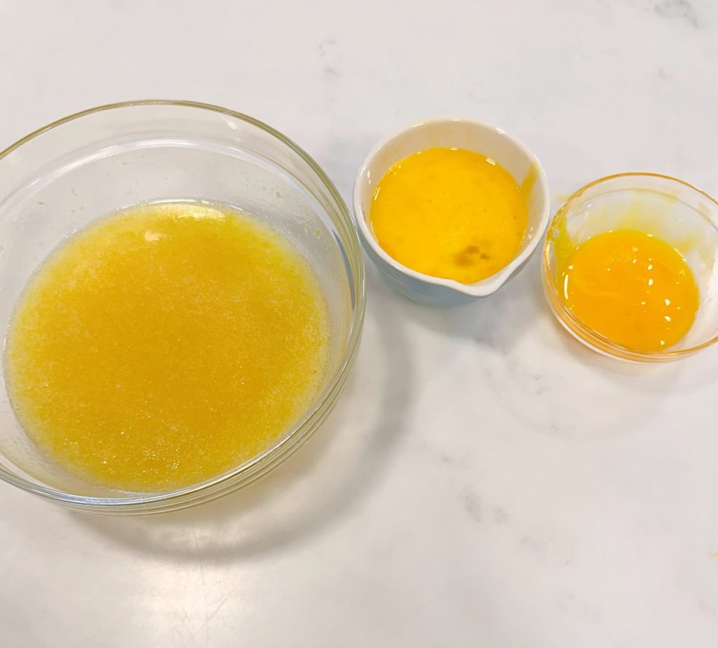 Egg yolks and beaten eggs being added to lemon and sugar mixture.