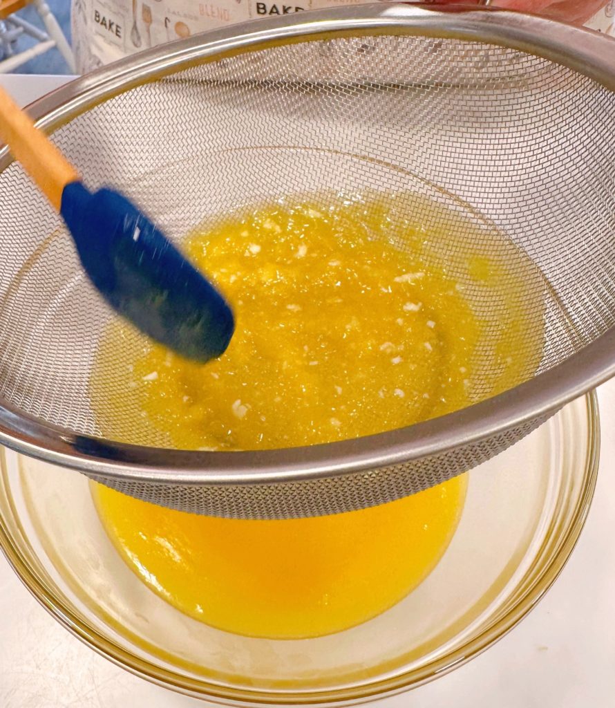 Pouring curd through metal sieve.