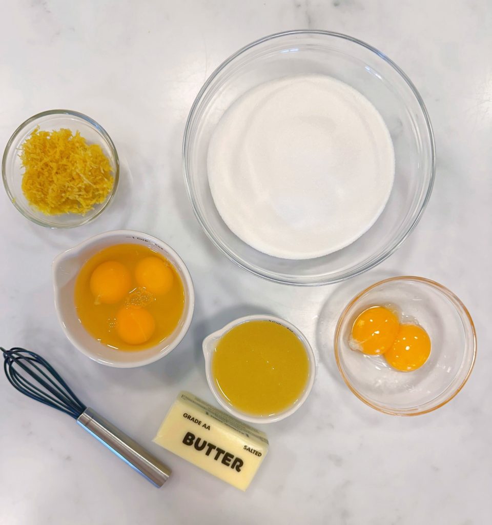 Ingredients for lemon curd in bowls on a white counter top.