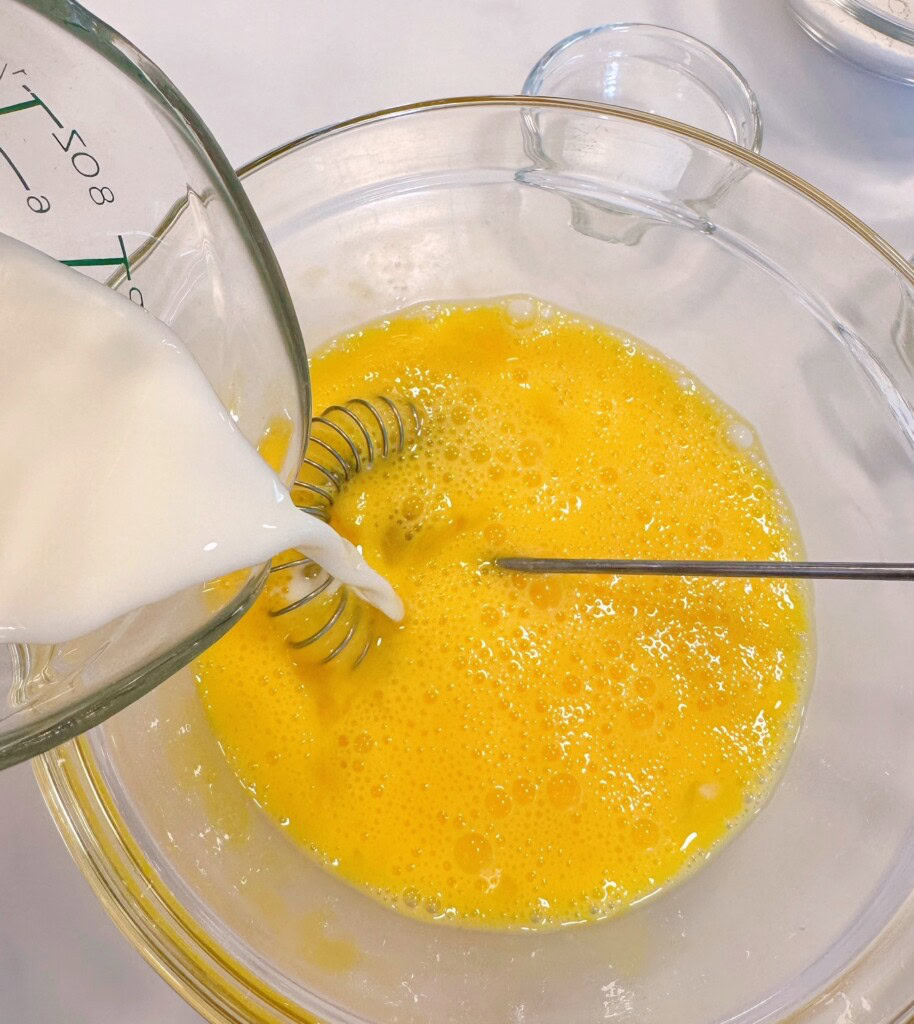 Adding milk to beaten eggs.