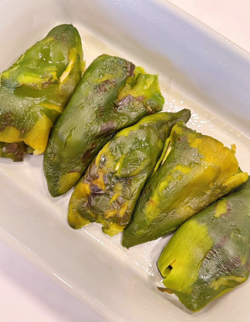 Stuffed chili peppers arranged in a casserole dish.