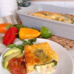 Chili Relleno Casserole with a serving on a dinner plate, cheese oozing out with salsa, and avocado slices.