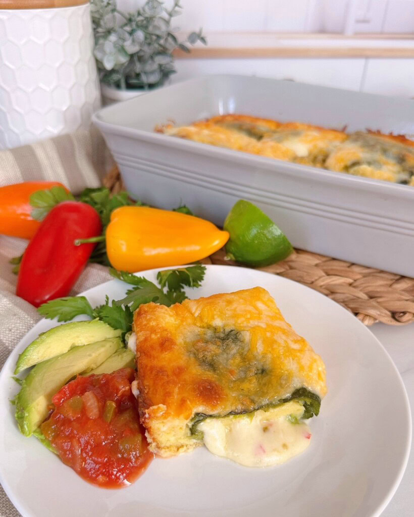Chili Relleno Casserole with a serving on a dinner plate, cheese oozing out with salsa, and avocado slices.