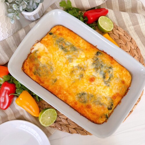 Chili Relleno Casserole in a grey casserole dish surround by peppers and limes.