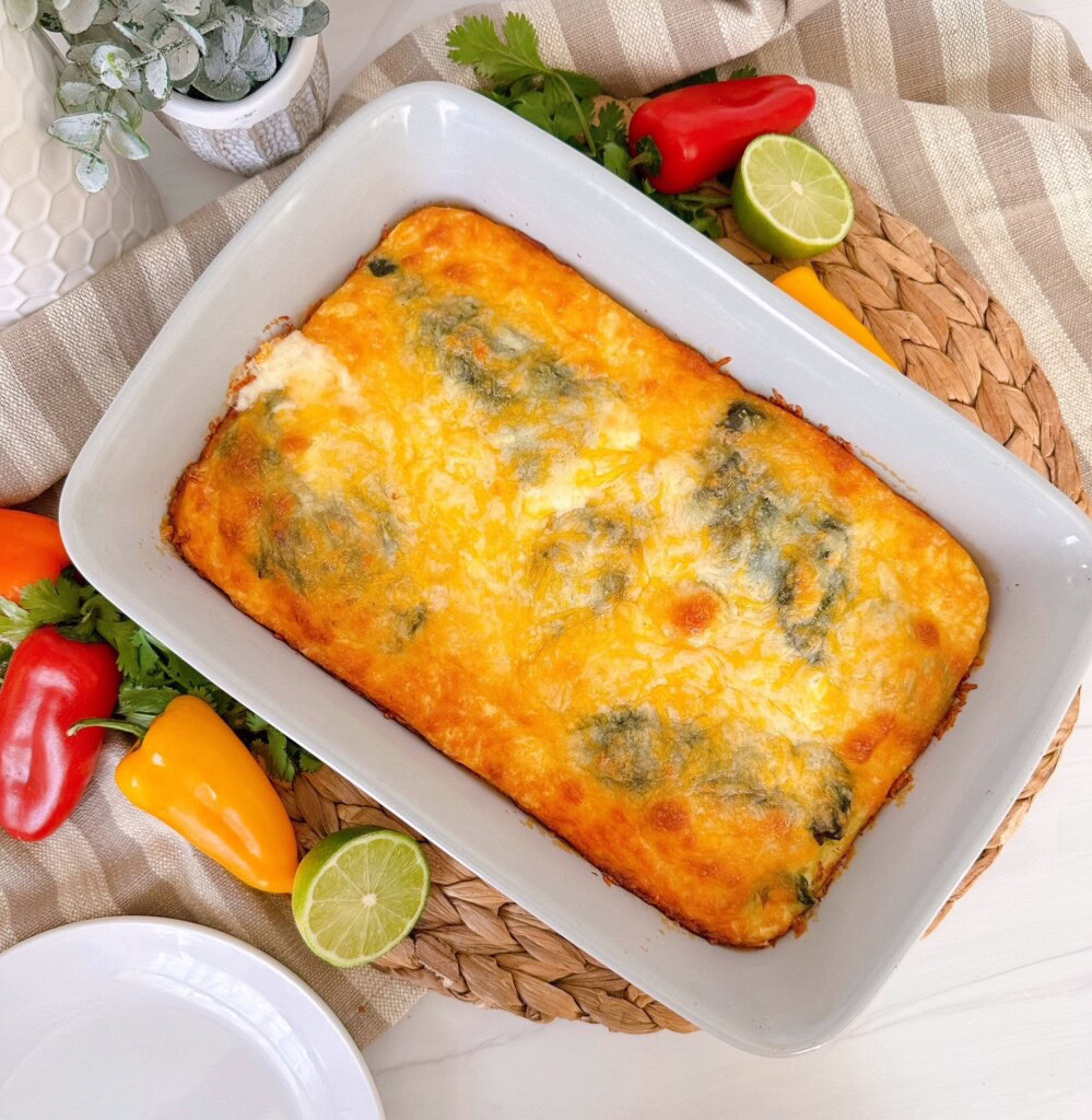 Chili Relleno Casserole in a grey casserole dish surround by peppers and limes.