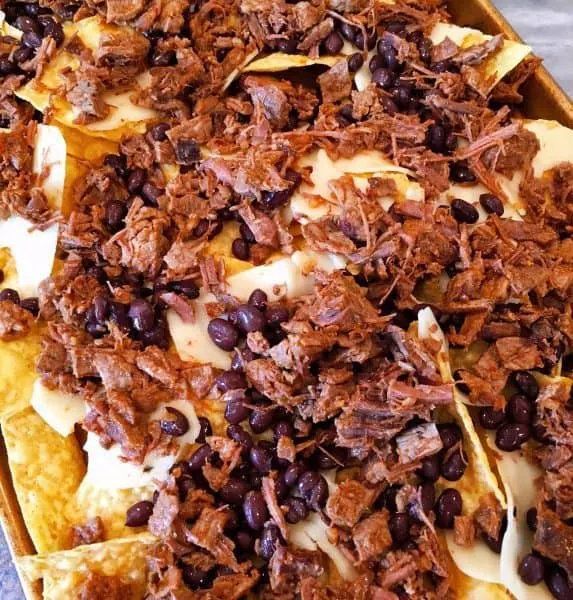 Tortilla chips topped of with cheese, meat, and beans 